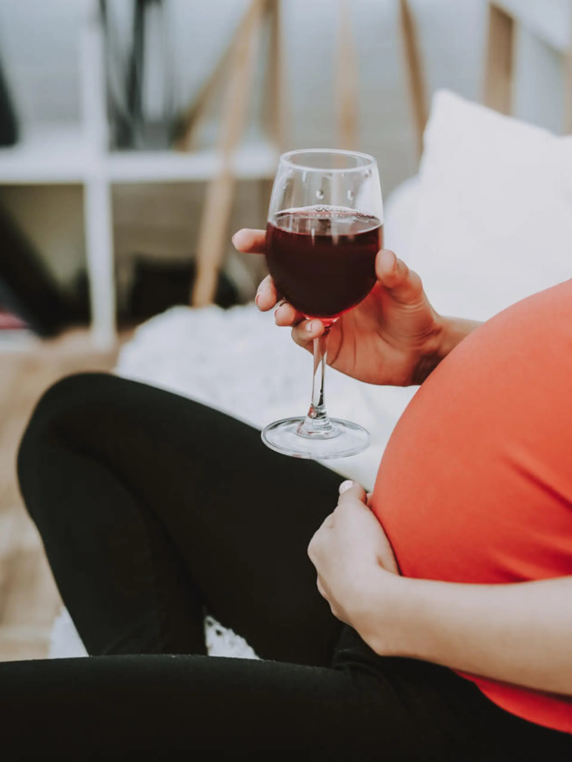 Schwangere Frau trinkt einen Wein.