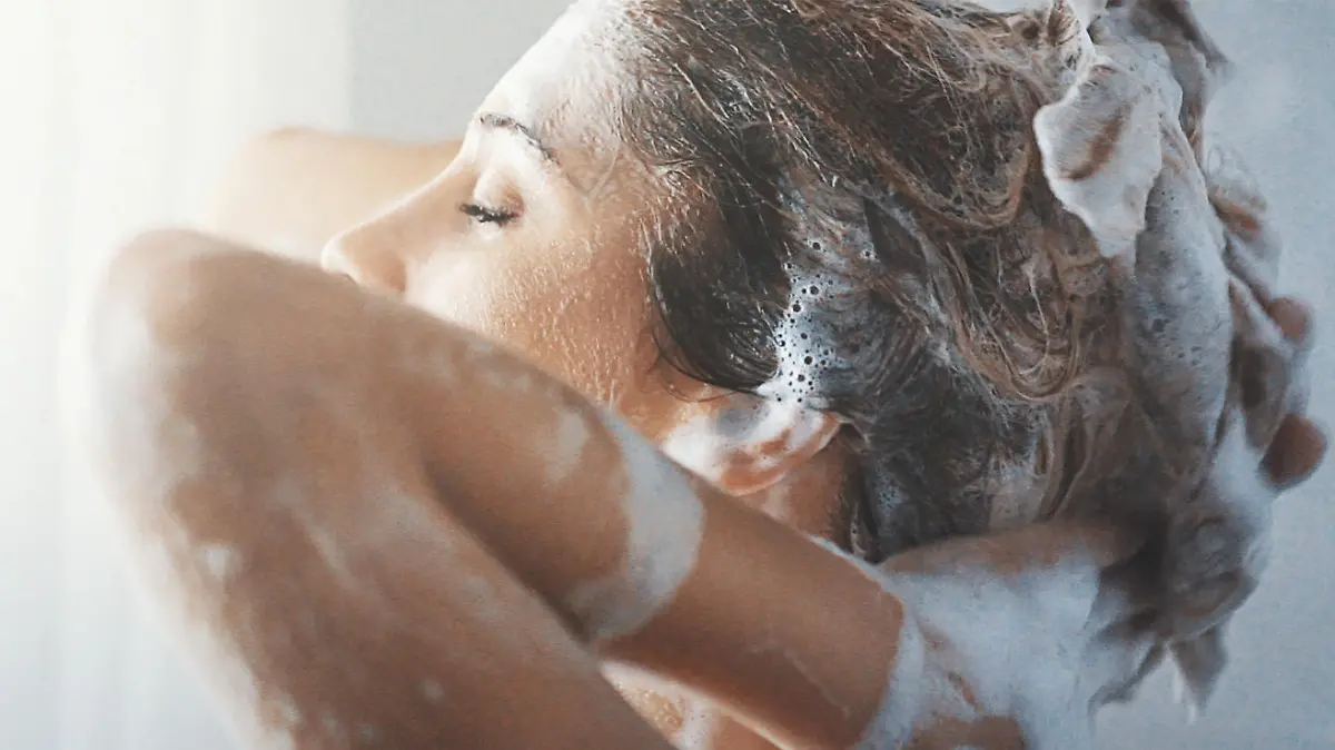 Eine Frau wäscht sich die Haare in der Dusche