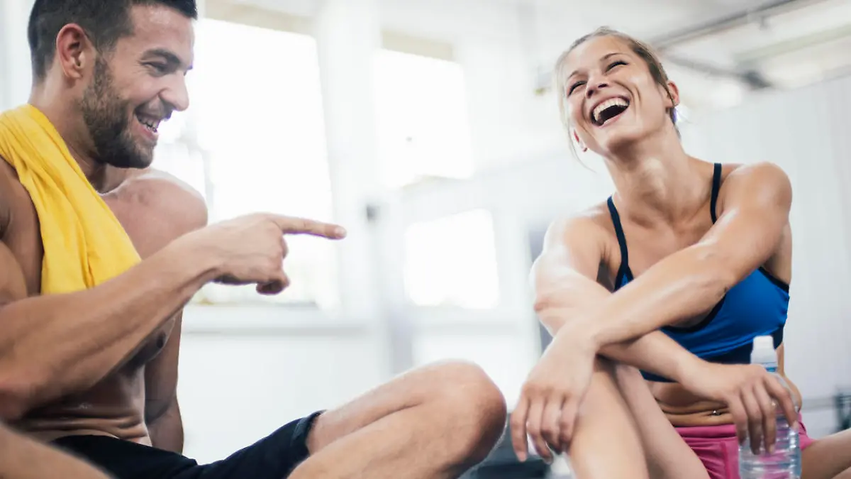 Happy young couple resting after hard workout in the gym