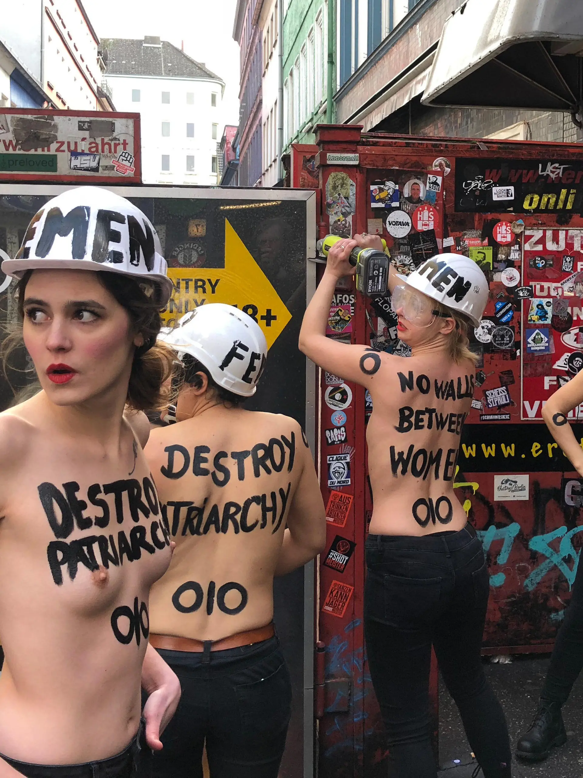 08.03.2019, Hamburg: Mit nacktem Oberkörper und einer Flex demontieren Aktivistinnen im Rotlichtviertel von St. Pauli einen Sichtschutz der Herbertstraße. Mit dieser Aktion will die Organisation Femen «die sexuelle Ausbeutung von Frauen, Menschenhandel und sexuelle Gewalt anprangern, die sich hinter den Toren und Türen der Sexindustrie versteckt», wie die Gruppe am Freitag auf ihrer Facebook-Seite mitteilte. (zu dpa "Halbnackte Frauen zerlegen Sichtschutz in Hamburgs Rotlichtviertel") Foto: Carina Lue/dpa +++ dpa-Bildfunk +++