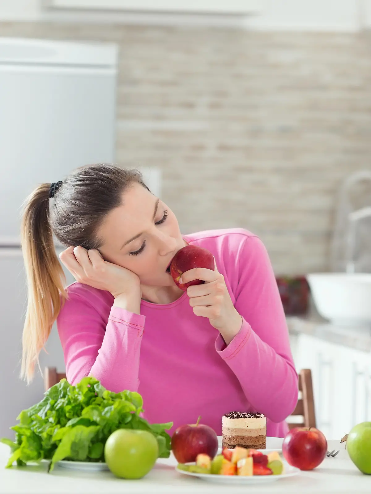 Frau sitzt mit Obst am Tisch