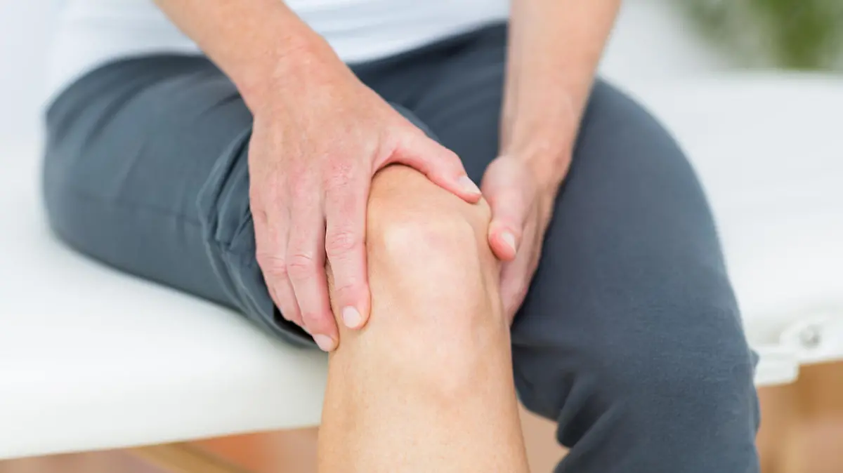Eine Frau hält sich das Knie