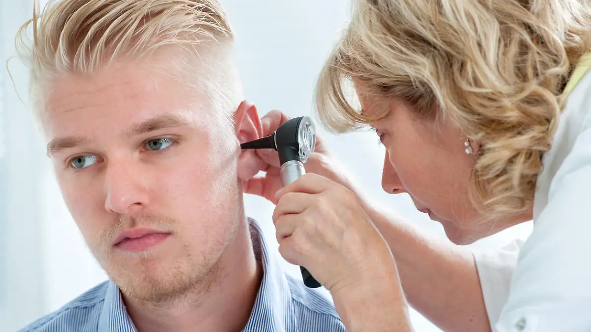 Eine Ohrenärztin untersucht einen jungen Mann