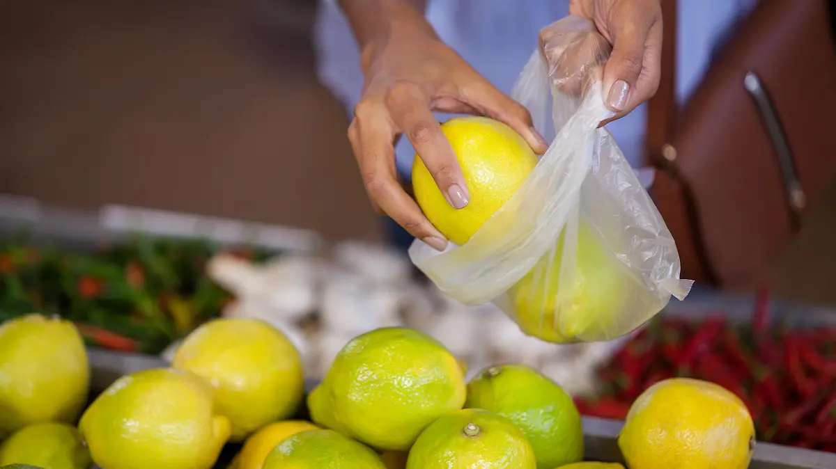 Frau packt beim Einkaufen Obst in eine Plastiktüte.