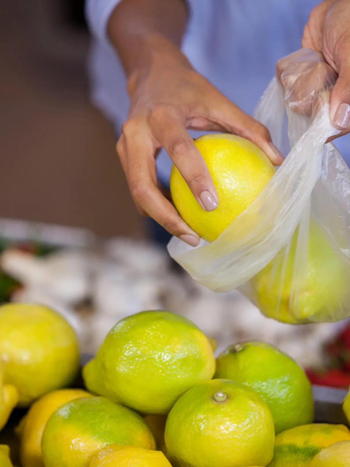 Frau packt beim Einkaufen Obst in eine Plastiktüte.