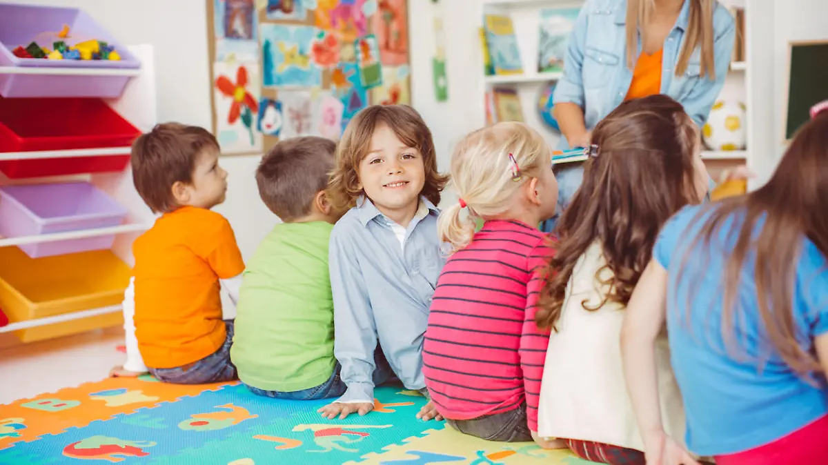 Kinder sitzen in der Kita und hören zu.