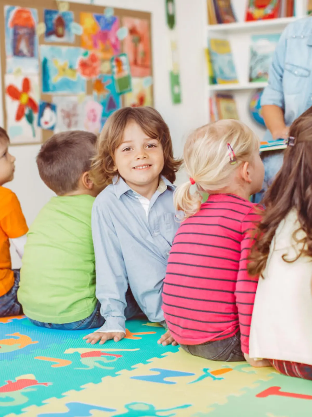 Kinder sitzen in der Kita und hören zu.
