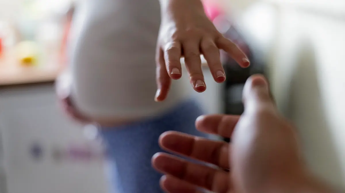 Schwangere Frau bekommt eine helfende Hand gereicht