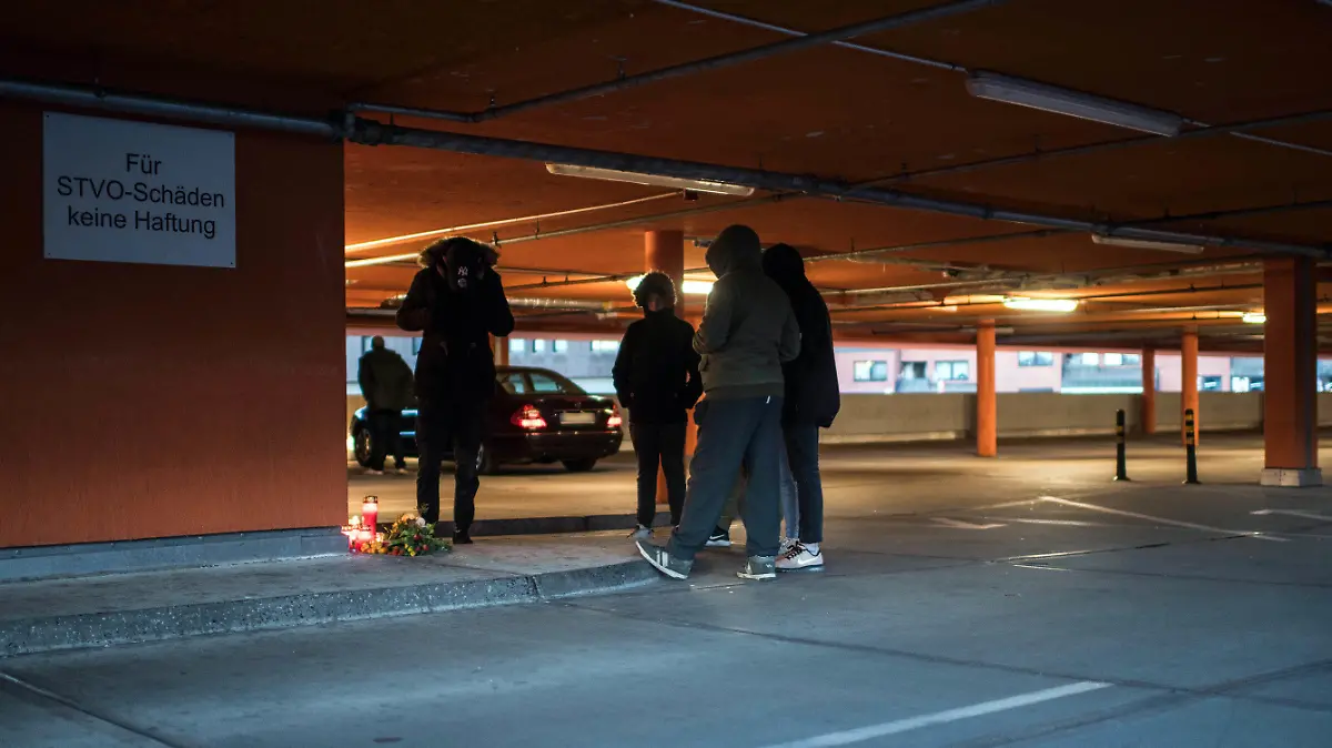 24.02.2018, Nordrhein-Westfalen, Dortmund: Jugendliche stehen um Kerzen und Blumen, die auf einem Parkdeck am Bahnhof im Stadtteil Hörde niedergelegt worden. Eine 15-Jährige ist am Freitag mit einem Messerstich tödlich verletzt worden. Zuvor hatte sie Streit mit einer 16-Jährigen gehabt. Die Jugendliche sei trotz versuchter Reanimation im Krankenhaus gestorben. Die 16-Jährige wurde festgenommen, eine Mordkommission hat die Ermittlungen übernommen. Foto: Bernd Thissen/dpa - ACHTUNG: Das Auto-Kennzeichen wurde aus rechtlichen Gründen gepixelt +++ dpa-Bildfunk +++