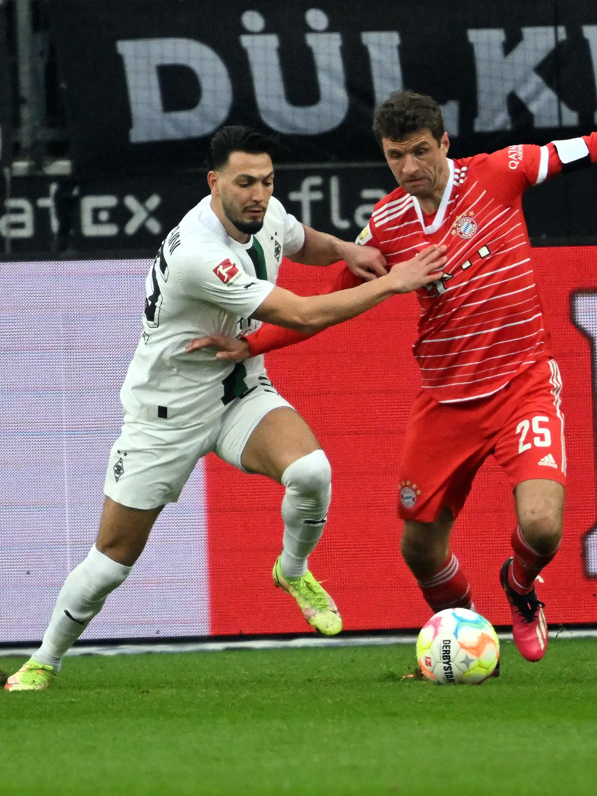 18.02.2023, Nordrhein-Westfalen, Mönchengladbach: Fußball: Bundesliga, Borussia Mönchengladbach - Bayern München, 21. Spieltag, Stadion im Borussia-Park: Mönchengladbachs Ramy Bensebaini (l) und Bayerns Thomas Müller kämpfen um den Ball. (zu dpa: «Frühste Auswechslung: Müller nimmt es hin, Hamann kritisiert») Foto: Federico Gambarini/dpa - WICHTIGER HINWEIS: Gemäß den Vorgaben der DFL Deutsche Fußball Liga bzw. des DFB Deutscher Fußball-Bund ist es untersagt, in dem Stadion und/oder vom Spiel angefertigte Fotoaufnahmen in Form von Sequenzbildern und/oder videoähnlichen Fotostrecken zu verwerten bzw. verwerten zu lassen. +++ dpa-Bildfunk +++