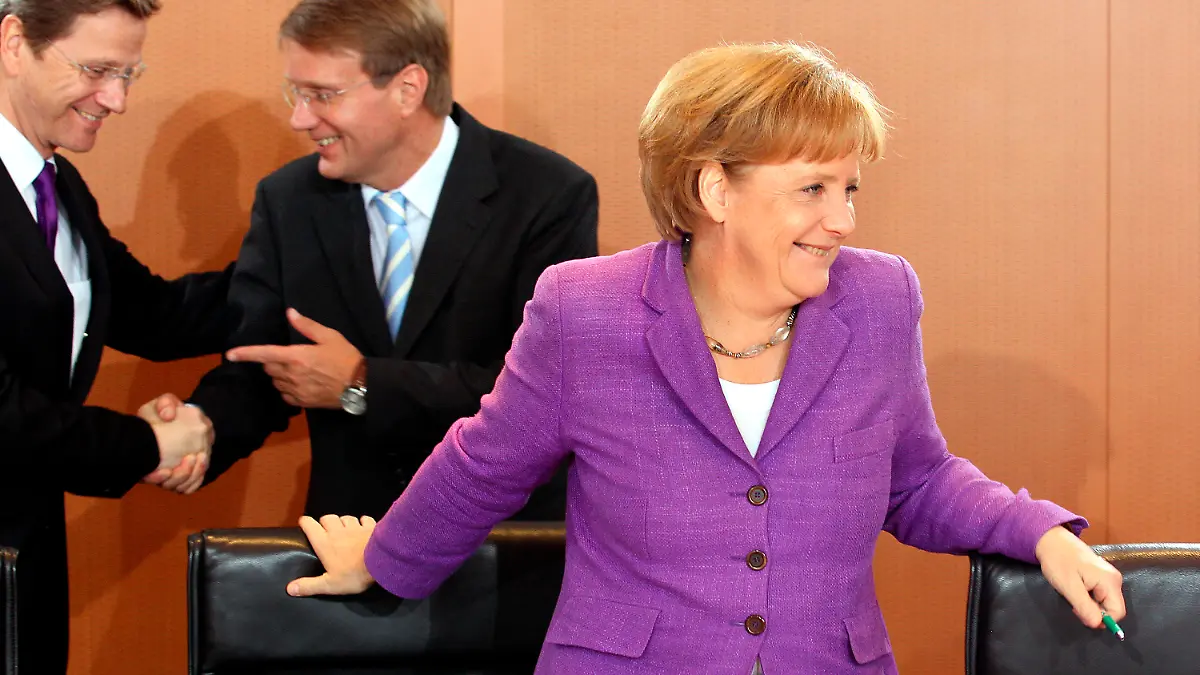 Lachend steht Bundeskanzlerin Angela Merkel (CDU) am Mittwoch (02.06.2010) zu Beginn der Kabinettssitzung im Bundeskanzleramt in Berlin am Konferenztisch, während sich im Hintergrund Bundesaußenminister Guido Westerwelle (FDP, l) und Kanzleramtsminister Ronald Pofalla (CDU) begrüßen. Foto: Wolfgang Kumm dpa/lbn  +++(c) dpa - Bildfunk+++