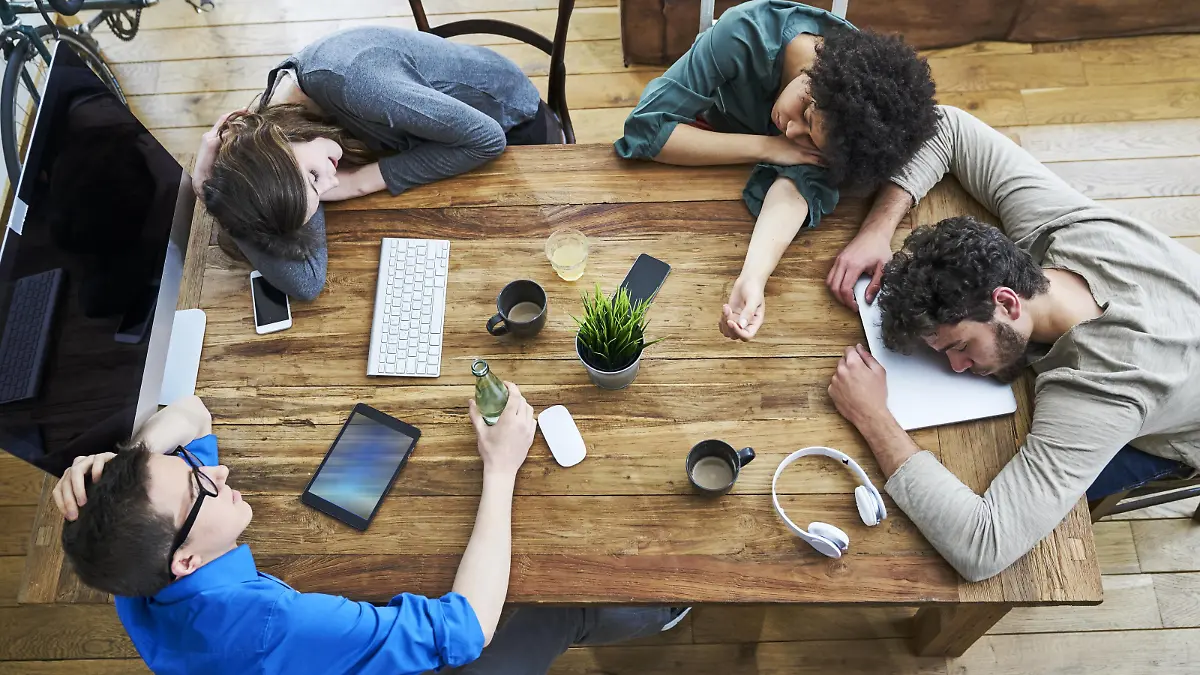 Elevated view of exhausted coworkers at wooden table in office model released Symbolfoto property released PUBLICATIONxINxGERxSUIxAUTxHUNxONLY FMKF04843  