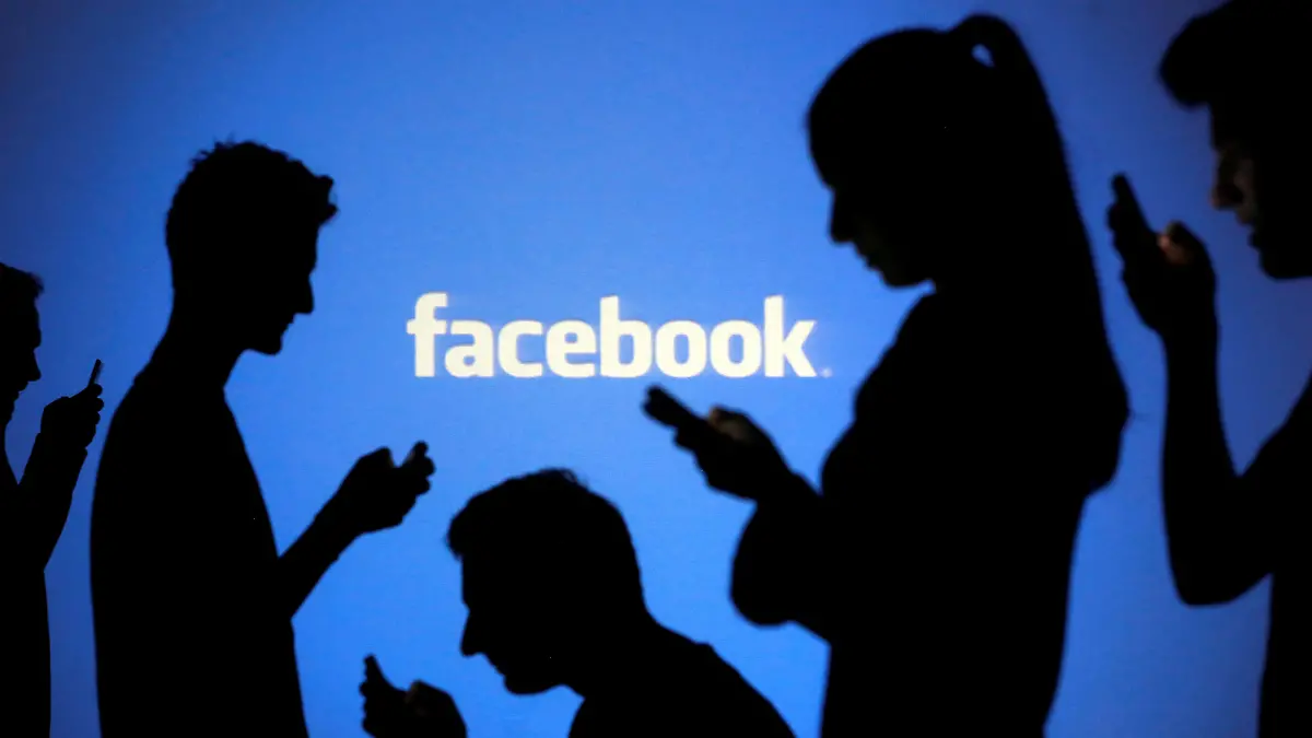 FILE PHOTO: People are silhouetted as they pose with mobile devices in front of a screen projected with a Facebook logo, in this picture illustration taken in Zenica, October 29, 2014. REUTERS/Dado Ruvic/File Photo