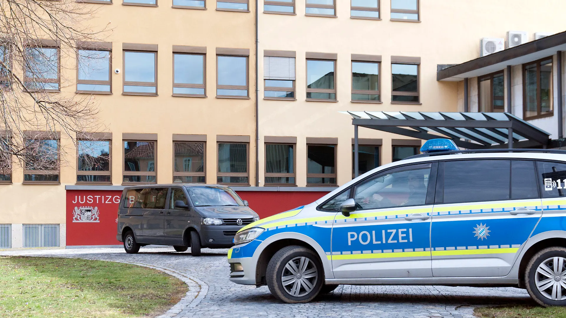 20.02.2023, Bayern, Coburg: Vor dem Justizgebäude I in Coburg sind Polizeiautos zu sehen. Aus dem Landgericht Coburg ist am Montag während einer Verhandlung ein 47 Jahre alter Angeklagter entkommen. Die Polizei hat eine Großfahndung nach dem Mann eingeleitet. (zu dpa: «47-Jähriger flüchtet während Gerichtsverhandlung aus Landgericht»). Foto: Pia Bayer/dpa +++ dpa-Bildfunk +++