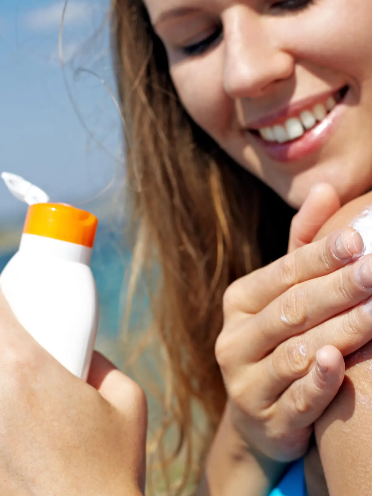 Young woman applying sunscreen 