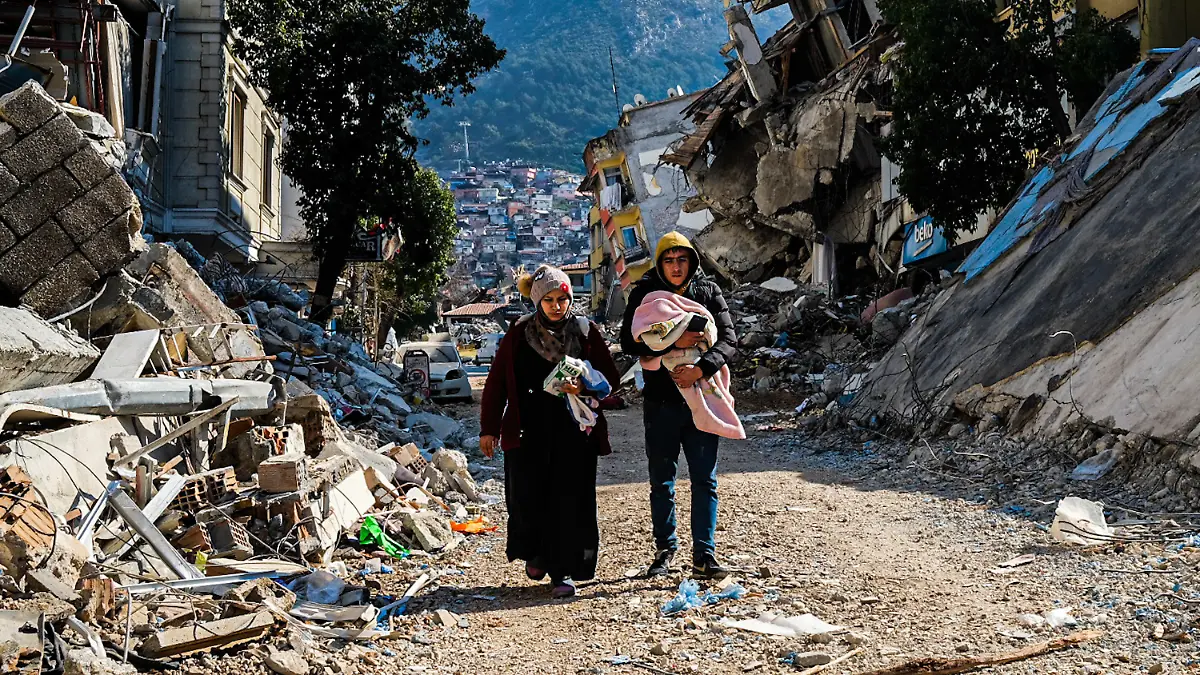 dpatopbilder - 12.02.2023, Türkei, Hatay: Eine Frau und ein junger Mann gehen durch die Trümmer des verheerenden Erdbebens vom 06.02.2023. Eine Woche nach dem Erdbeben im türkisch-syrischen Grenzgebiet ist die Zahl der Toten auf mehr als 30 000 gestiegen. Foto: Murat Kocabas/SOPA Images via ZUMA Press Wire/dpa +++ dpa-Bildfunk +++