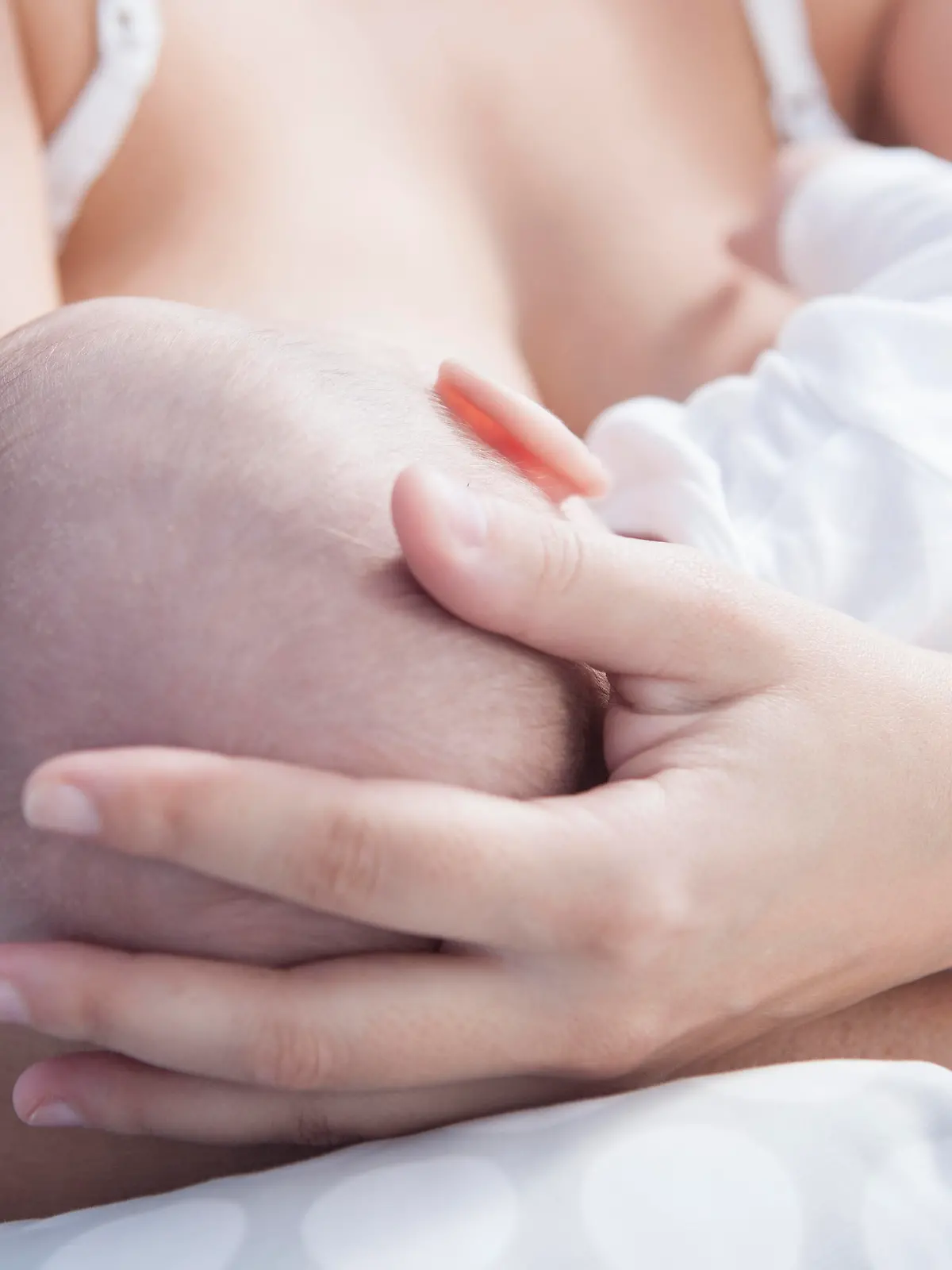 Mutter hält beim Stillen den Kopf ihres Babys