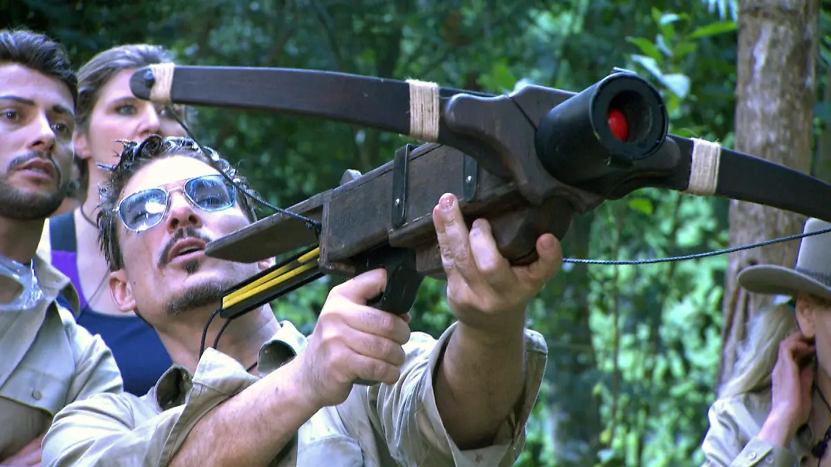 Tag 1 - Dschungelprüfung "Starschuss". Chris Töpperwien hat mit seinem Mund zwei Bälle aus den Behältern voller Kakerlaken, Maden und Schleim rausgefischt. Die erkämpften Bälle dienen als Munition für eine Armbrust. Für jeden Treffer auf Tierschilder in einem Baum gibt es einen Stern.