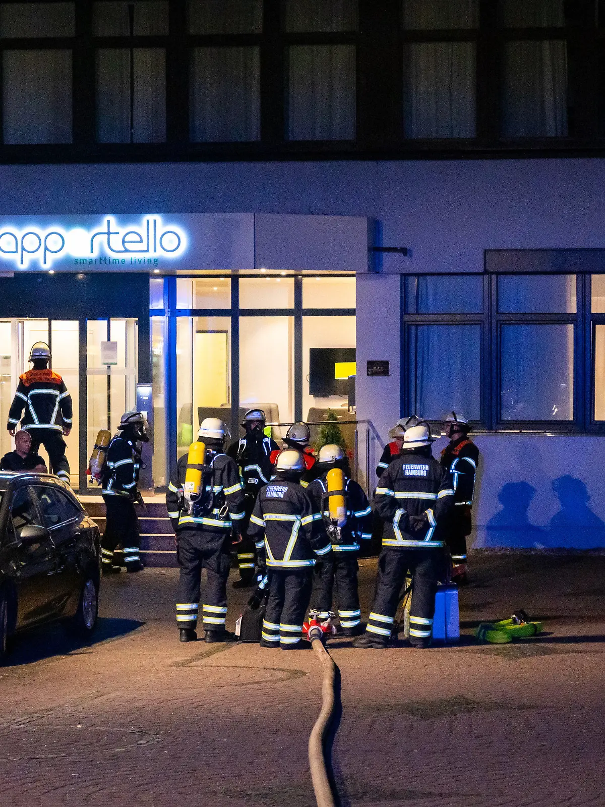 14.08.2023, Hamburg: Einsatzkräfte von Feuerwehr und Polizei stehen vor einem Hotel. Vor einem Hotel in Hamburg, in dem hauptsächlich ukrainische Flüchtlinge untergebracht sind, haben Müllcontainer und der dazugehörige Unterstand gebrannt. Foto: Jonas Walzberg/dpa +++ dpa-Bildfunk +++
