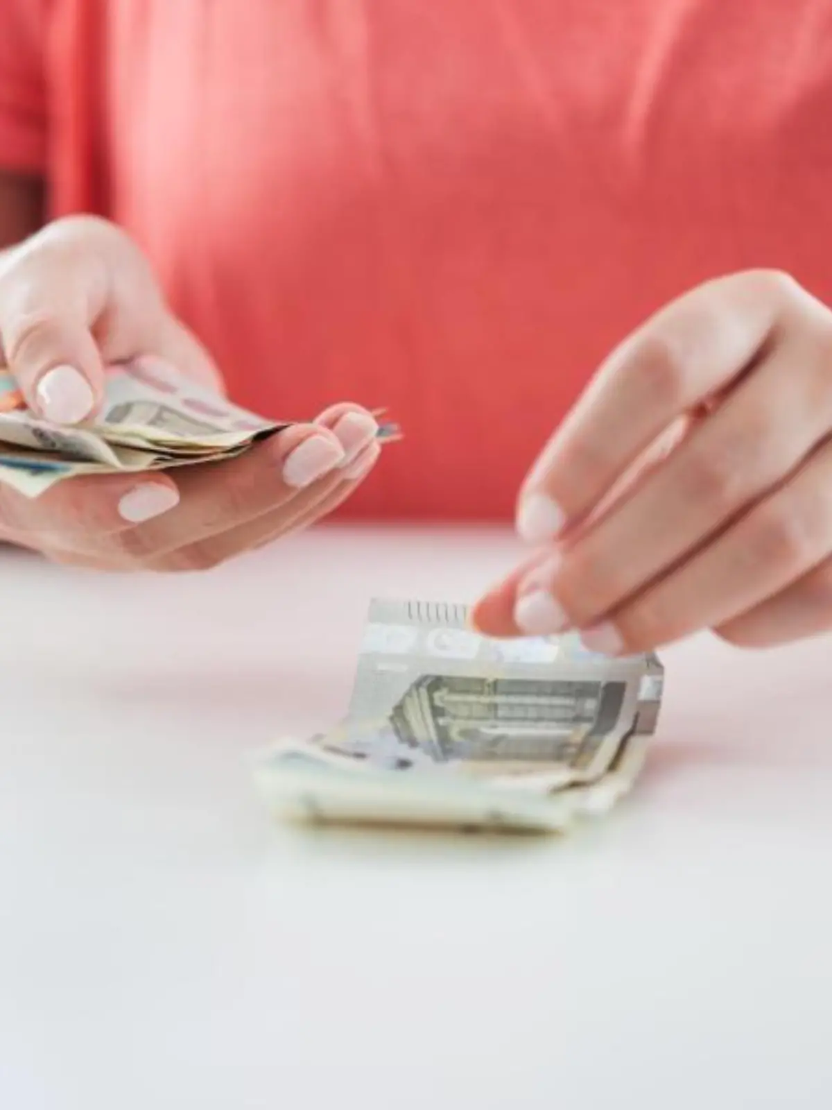 Eine Person stapelt 5-Euro-Scheine