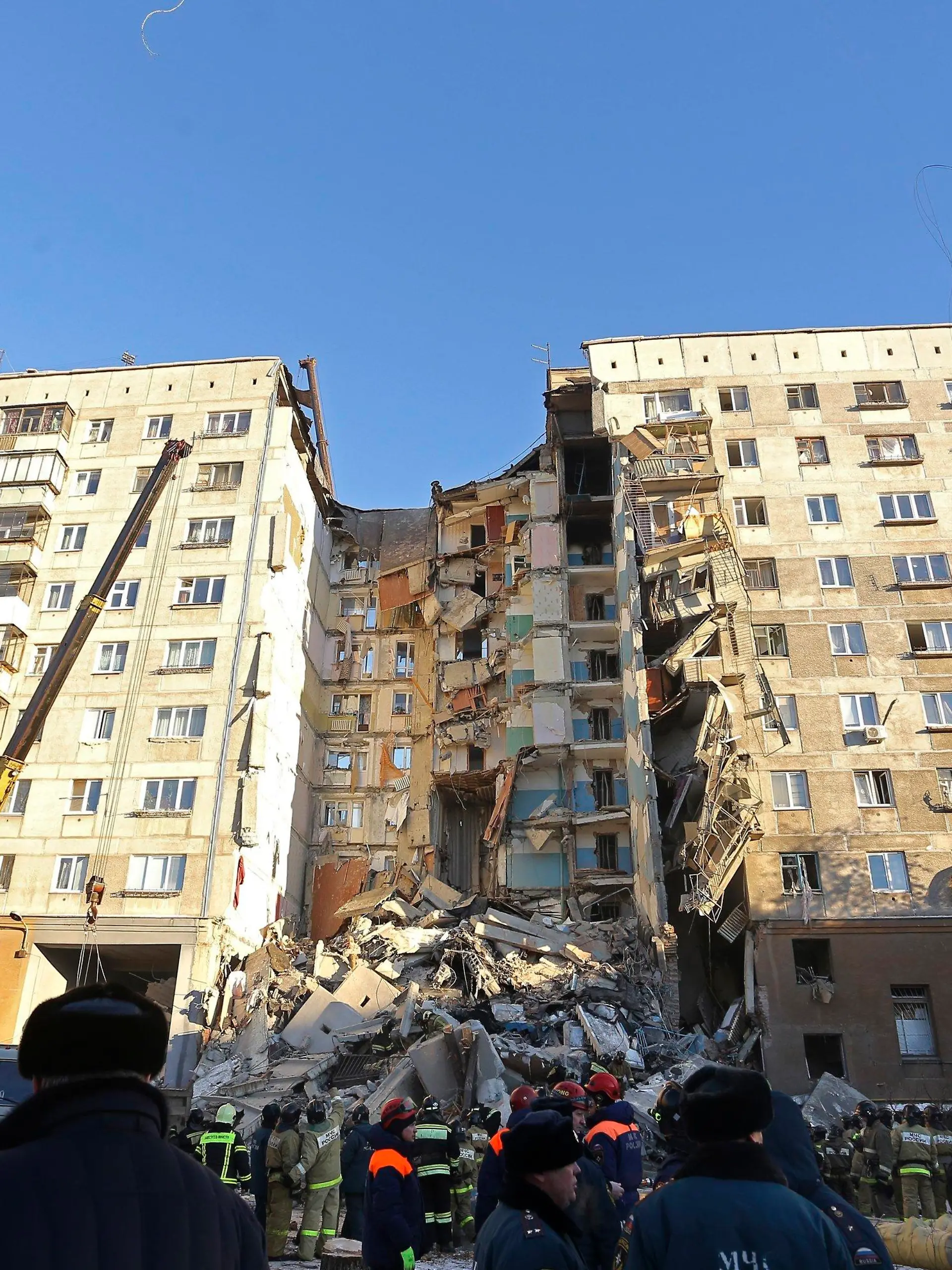 31.12.2018, Russland, Magnitogorsk: Rettungskräfte stehen vor einem Wohnhaus, das durch eine Gasexplosion beschädigt worden ist. Bis zum Montagmittag (Ortszeit) sprachen die Behörden von mindestens vier Toten. Zehn Menschen seien verletzt gerettet worden. Foto: Maxim Shmakov/AP/dpa +++ dpa-Bildfunk +++