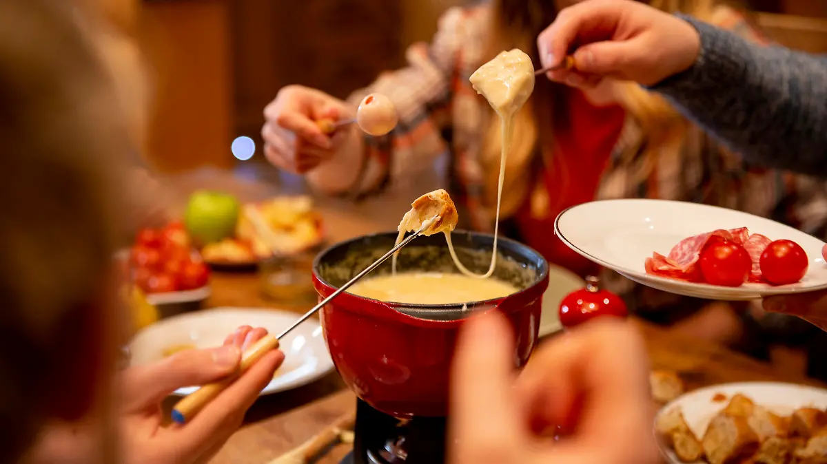 A group of work colleagues eat fondue together on a team bonding trip.