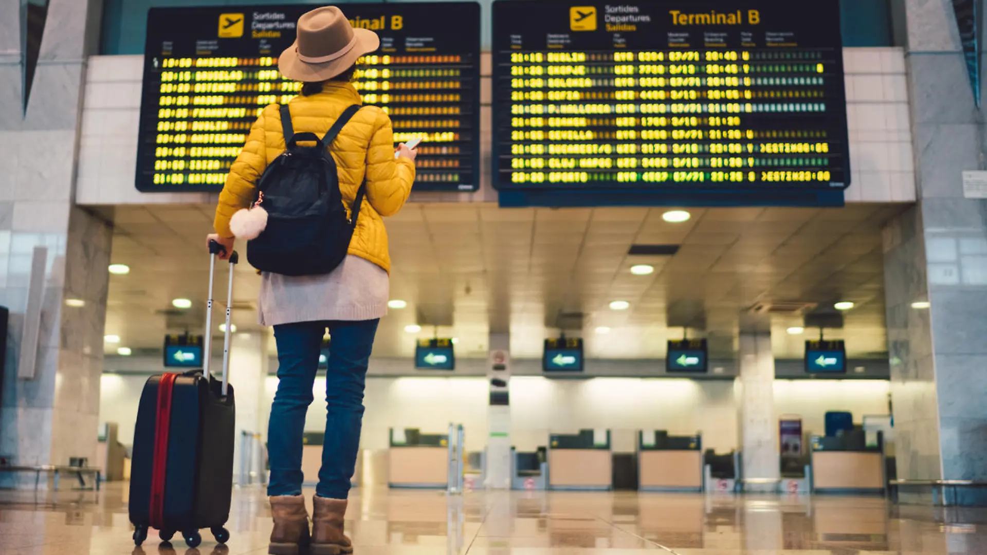 Young woman at the airport in Barcelona checking for the flight schedule