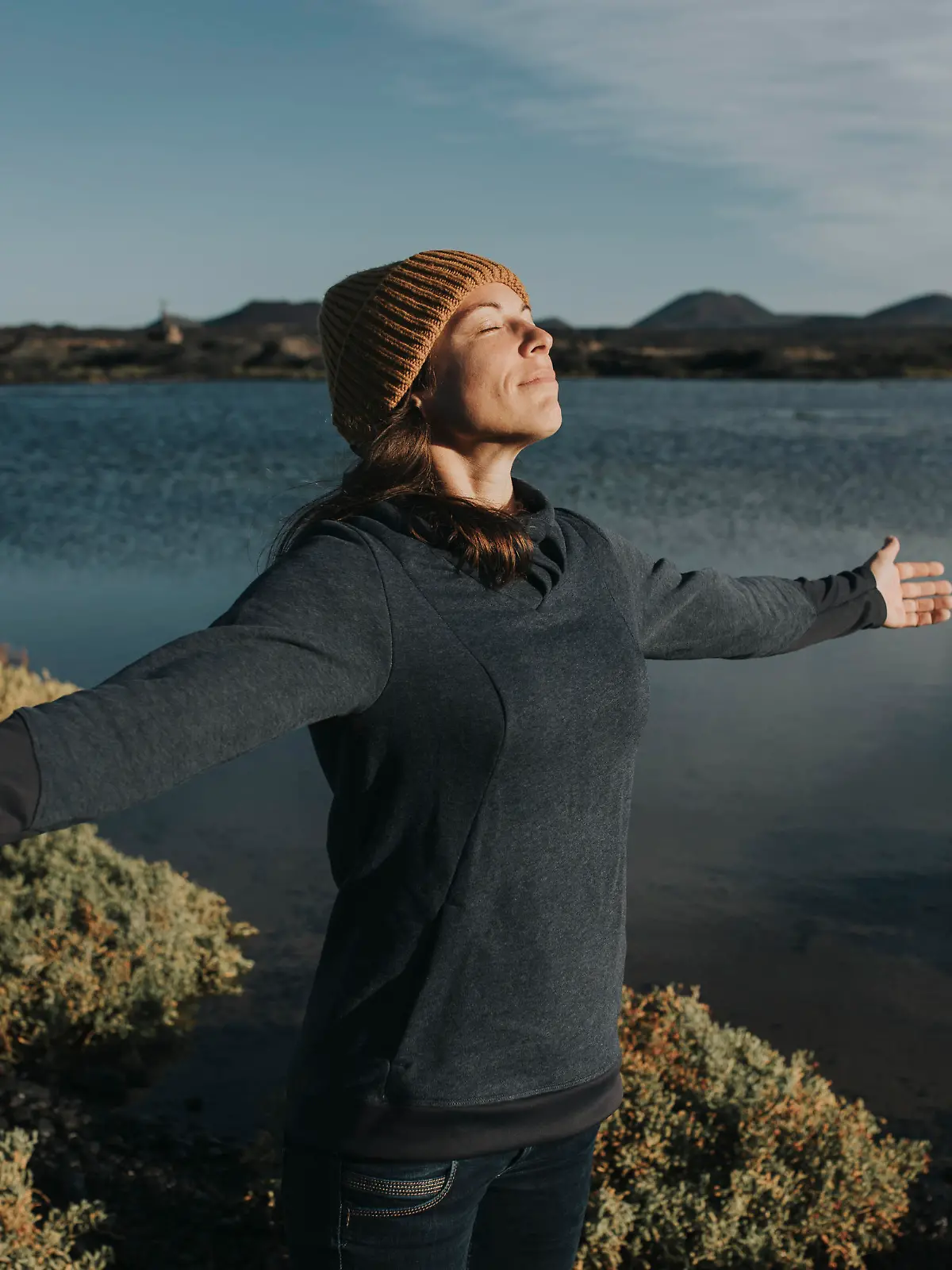 Woman with arms outstretched enjoying sunlight at lake || Modellfreigabe vorhanden