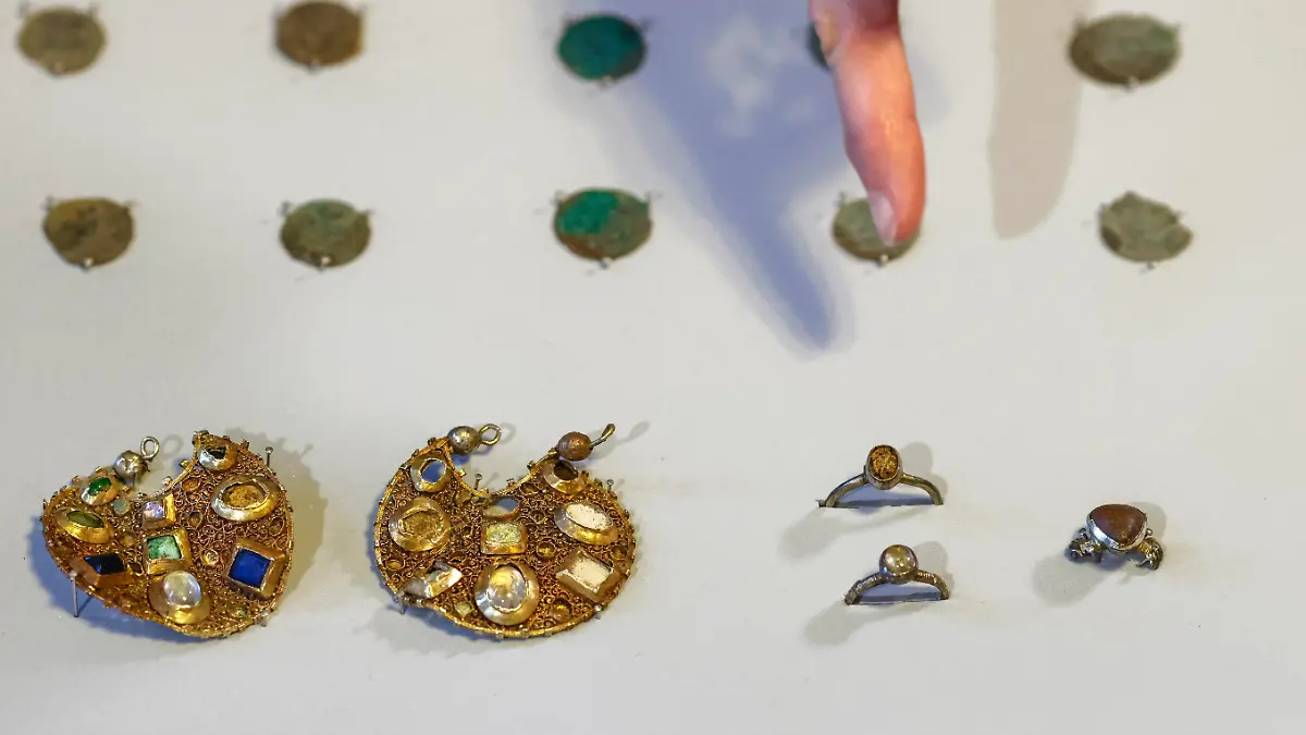 17.02.2023, Schleswig-Holstein, Schleswig: Eine Mitarbeiterin des Archäologischen Landesamtes Schleswig-Holstein deutet mit dem Finger auf zwei Ohranhänger. Mitarbeiter des Landesamtes hatten mit Hilfe von Detektoren den Schmuck aus der Zeit um 1100 gefunden. Laut Landesamt wurde der Schmuck vermutlich vor rund 800 Jahren von einem Reisenden versteckt. Foto: Frank Molter/dpa +++ dpa-Bildfunk +++