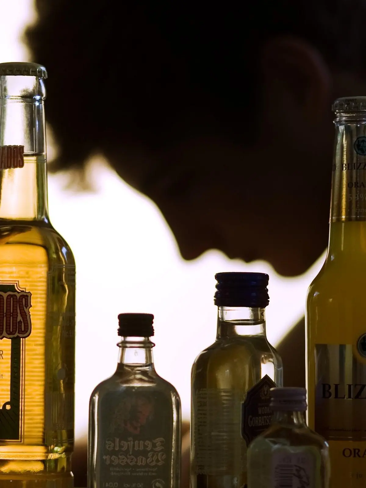 ARCHIV - Ein Jugendlicher sitzt hinter Flaschen mit Alkohol in Schwerin (Illustration vom 07.09.2009). "Lieber schlau als blau" heißt das Pilotprojekt, das seit Herbst 2008 in Brandenburg läuft. Das Trinkexperiment in Schulen oder Clubs ist ein neuer Ansatz der Suchtprävention, um Jugendliche vom "Komasaufen" abzuhalten. Doch nicht alle Präventions-Strategen sind von der Idee begeistert. Die Hauptstadt Berlin, in der fast jede Woche Jugendliche mit Alkoholvergiftungen ins Krankenhaus kommen, sieht das eher kritisch. Foto: Jens Büttner dpa (zu dpa-Korr-Bericht: "Alkohol im Unterricht" vom 23.06.2010)  +++(c) dpa - Bildfunk+++