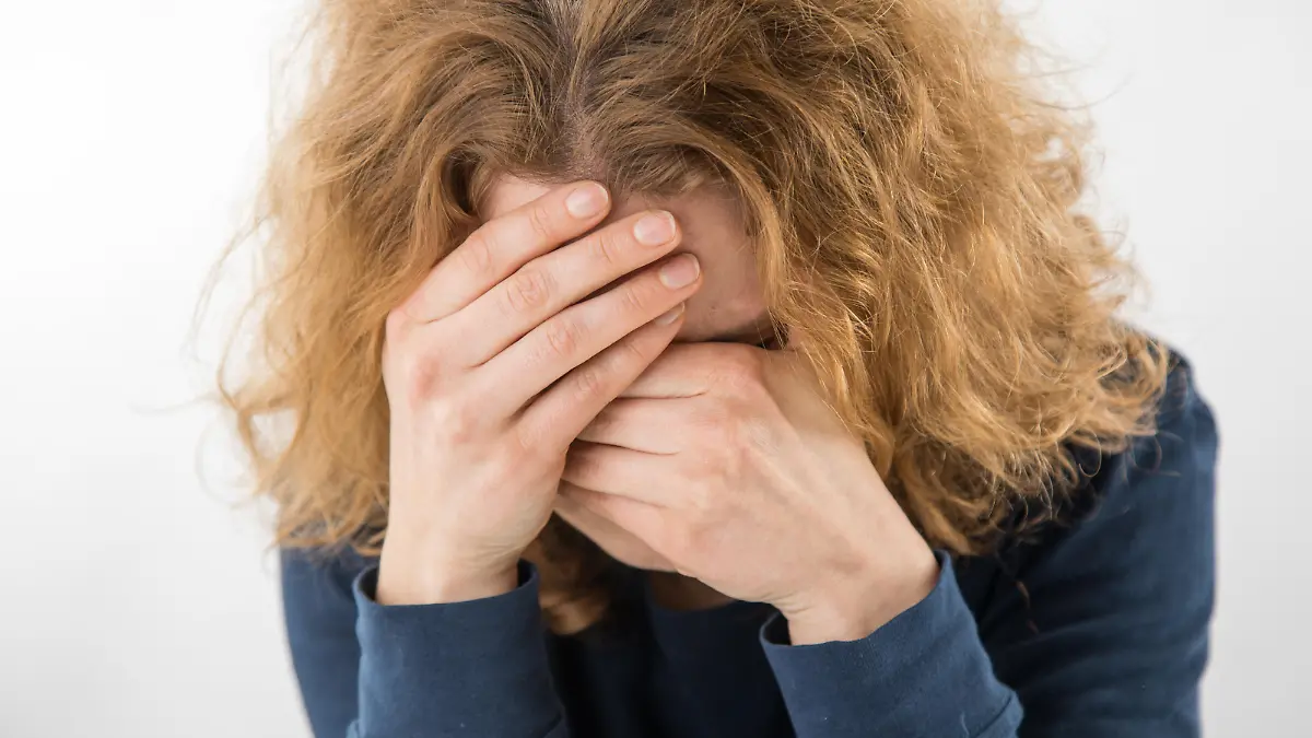 ILLUSTRATION - Eine Frau sitzt am 12.02.2019 in einem Studio in Hamburg und versteckt ihr Gesicht hinter ihren Haenden (gestellte Szene). Foto: Christin Klose | Verwendung weltweit