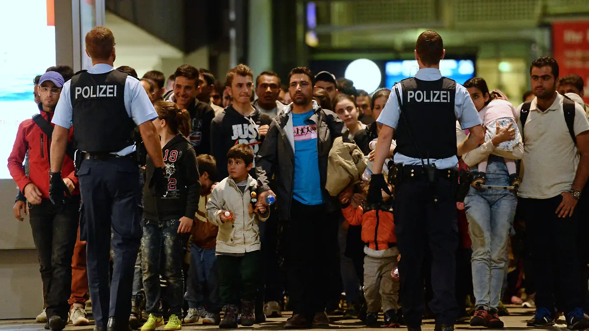 ARCHIV - Flüchtlinge kommen am 12.09.2015 mit einem Zug aus Budapest am Hauptbahnhof in München (Bayern) an und gehen von Polizisten begleitet durch den Bahnhof. Die Flüchtlingskrise stellt die Polizei vor enorme Herausforderungen. Die Überstunden gehen in die Millionen. Nicht alle anderen Aufgaben können wie bisher erfüllt werden. Foto: Andreas Gebert/dpa (zu dpa-Umfrage: "Belastung an vielen Fronten: Polizei durch Flüchtlinge im Stress" vom 22.09.2015) +++(c) dpa - Bildfunk+++