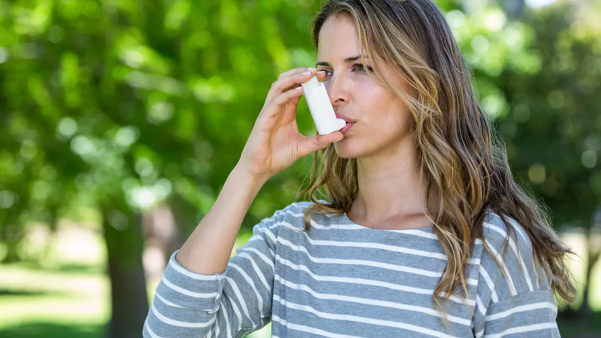 Woman using asthma inhaler in a park
