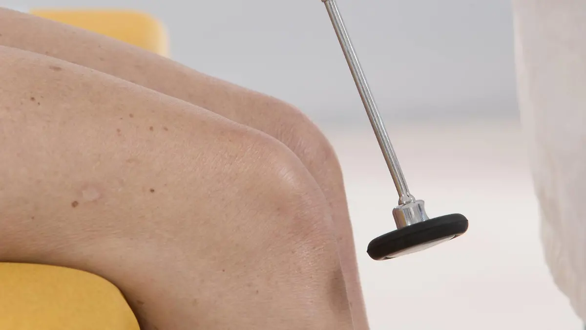 Ein Arzt prüft bei einer Patientin den Kniesehnenreflex