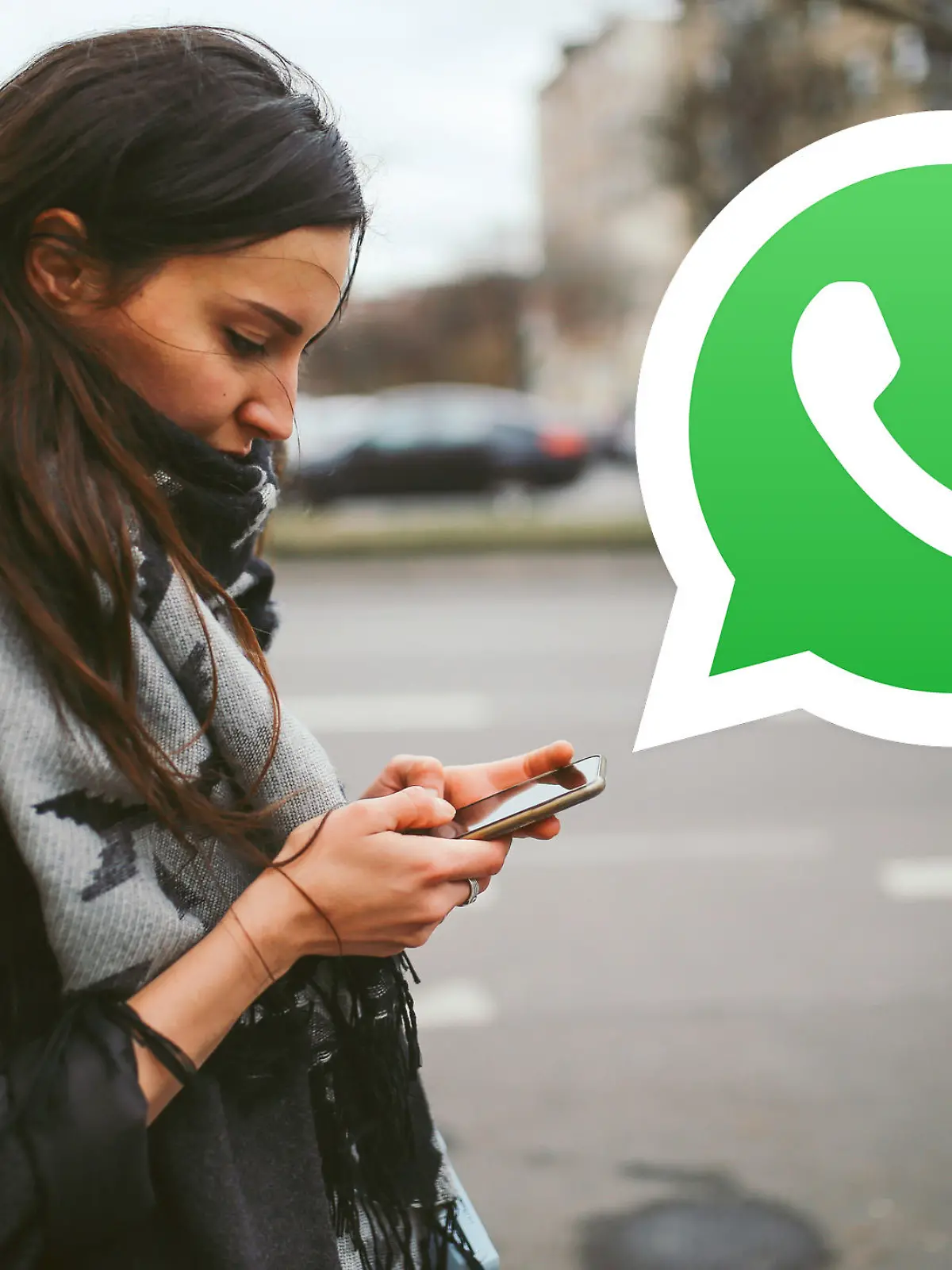 Frau mit Smartphone, großes Whatsapp-Logo