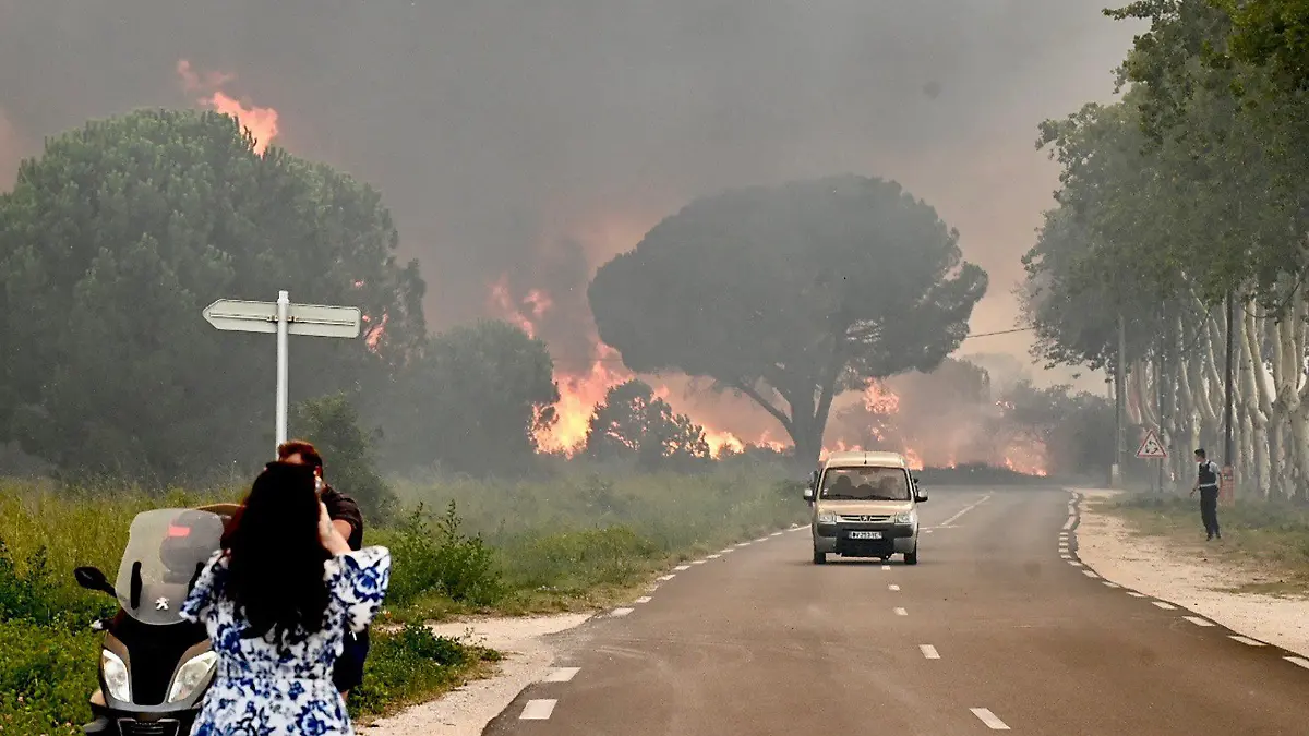 dpatopbilder - 14.08.2023, Frankreich, Argelès-Sur-Mer: Eine Frau fotografiert in Saint-Andre in der Nähe von Argeles-sur-Mer im Südwesten Frankreichs einen Großbrand, der zur Evakuierung  von rund 3000 Touristen von nahegelegenen Campingplätzen geführt hat. Foto: Raymond Roig/AFP/dpa +++ dpa-Bildfunk +++