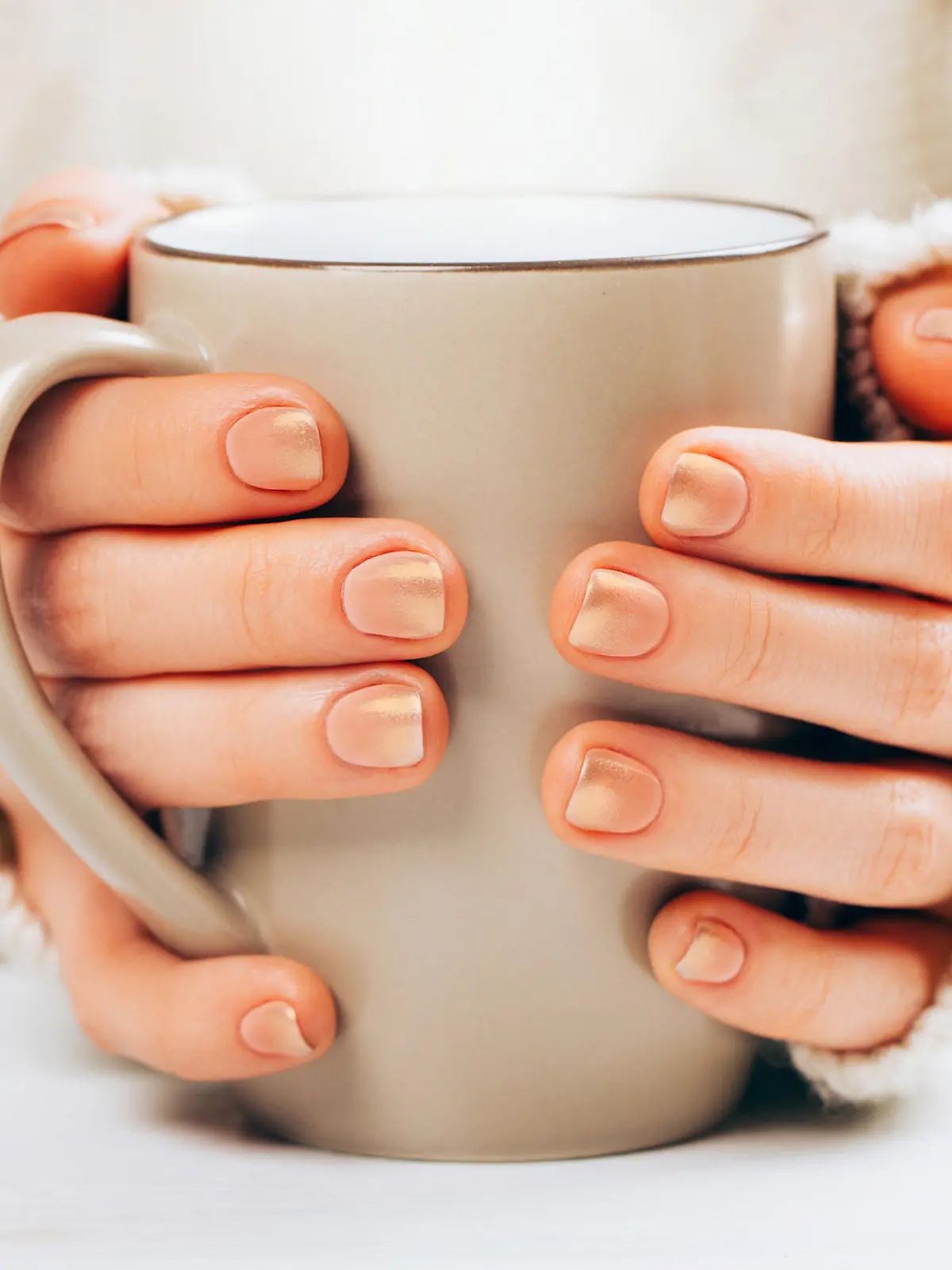 Frau mit Cappuccino Nails hält Kaffee.