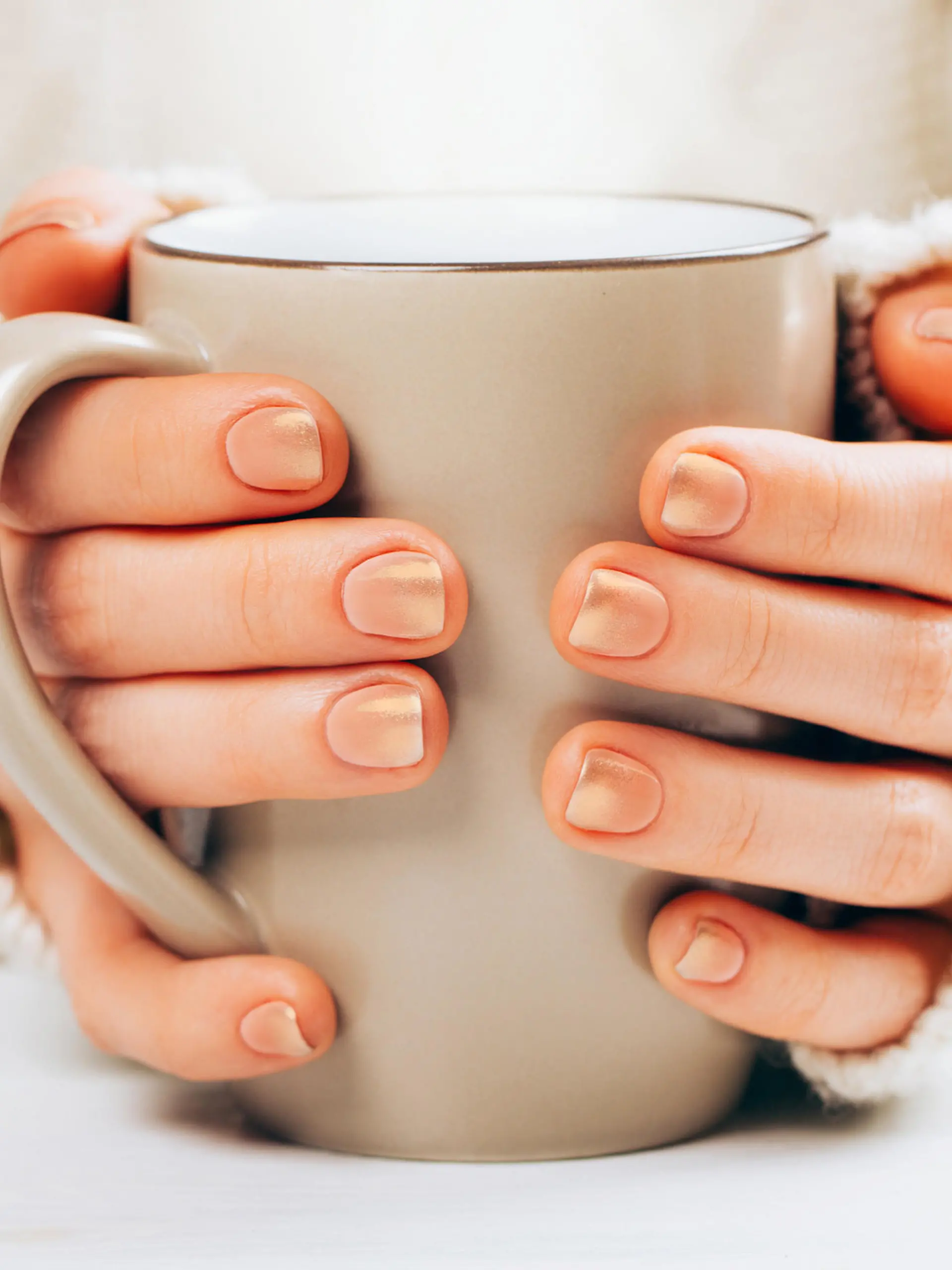 Frau mit Cappuccino Nails hält Kaffee.