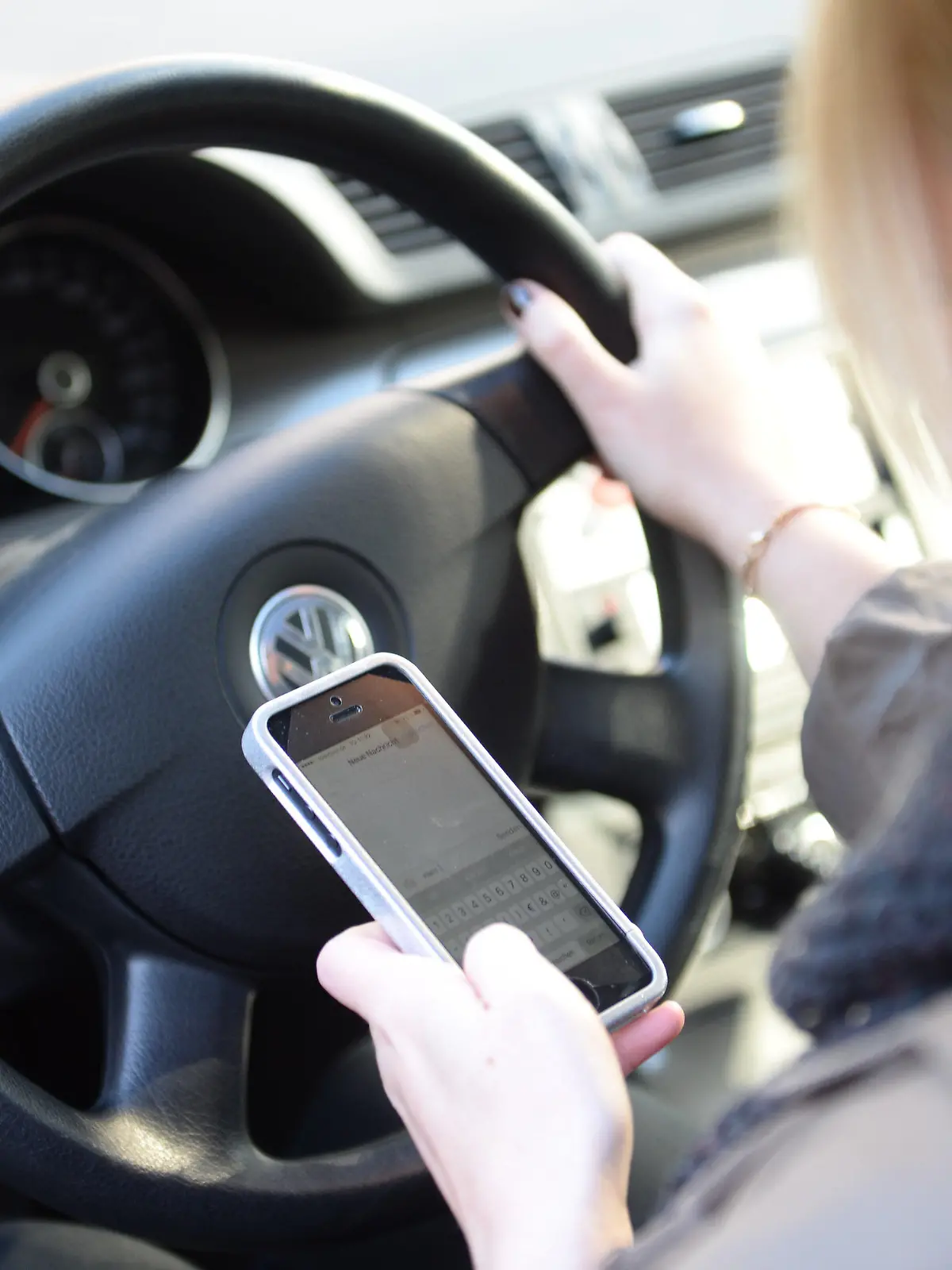ARCHIV - ILLUSTRATION - Eine Frau sitzt am 02.10.2015 in Düsseldorf (Nordrhein-Westfalen) im Auto am Steuer und liest Nachrichten auf ihrem Smartphone.     (zu dpa «Autofahrer mit Handy am Ohr - die Unsitte greift um sich» vom 10.03.2017) Foto: Monika Skolimowska/dpa +++(c) dpa - Bildfunk+++