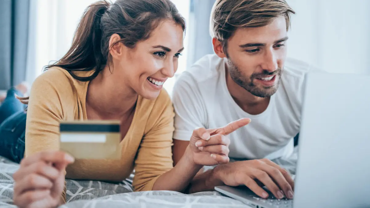 Young cheerful couple shopping online at home. Couple shopping online with credit card and laptop.