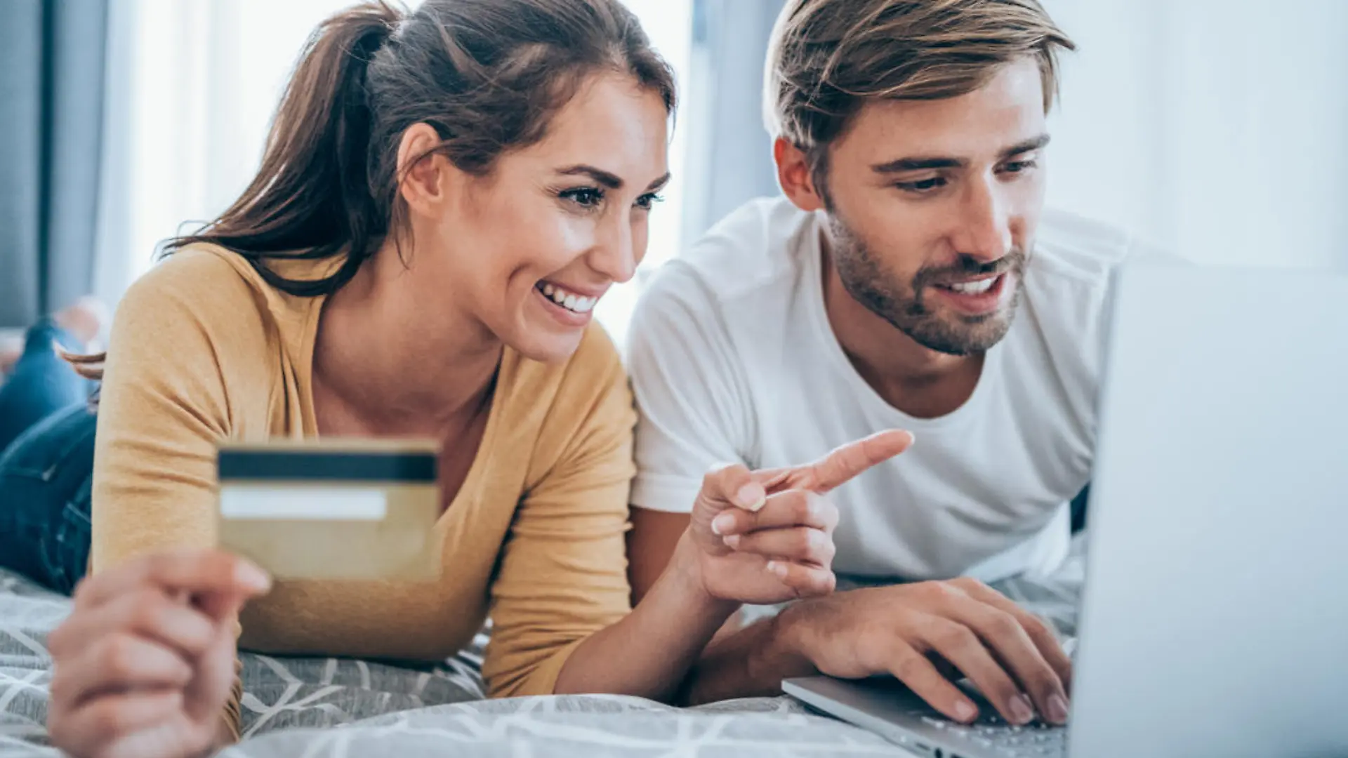 Young cheerful couple shopping online at home. Couple shopping online with credit card and laptop.