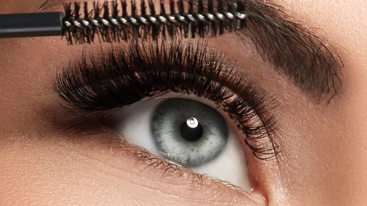 Frau trägt Mascara auf Wimpern auf.