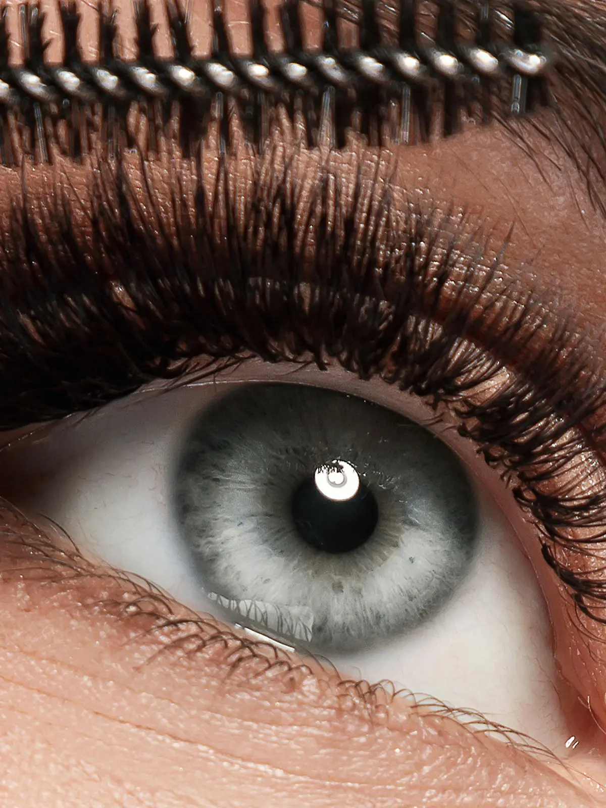 Frau trägt Mascara auf Wimpern auf.