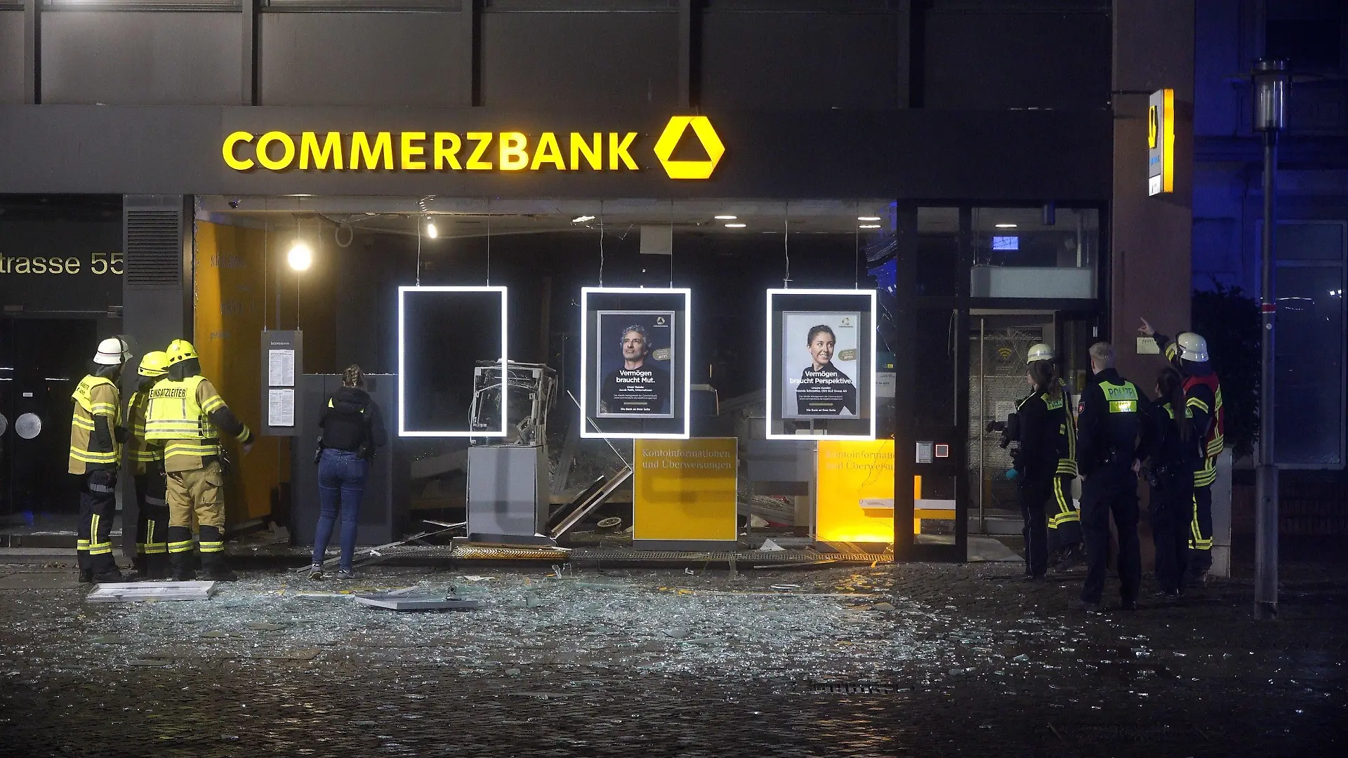 15.02.2023, Niedersachsen, Achim: Polizisten sind am Tatort im Einsatz. Unbekannte haben einen Geldautomaten in der Innenstadt von Achim (Landkreis Verden) gesprengt. Die Tat geschah am frühen Mittwochmorgen, wie die Polizei mitteilte. Dabei wurde die Glasfassade im unteren Bereich des Wohn- und Geschäftshauses, in dem der Automat stand, komplett zerstört. Foto: --/Nord-West-Media TV/dpa +++ dpa-Bildfunk +++