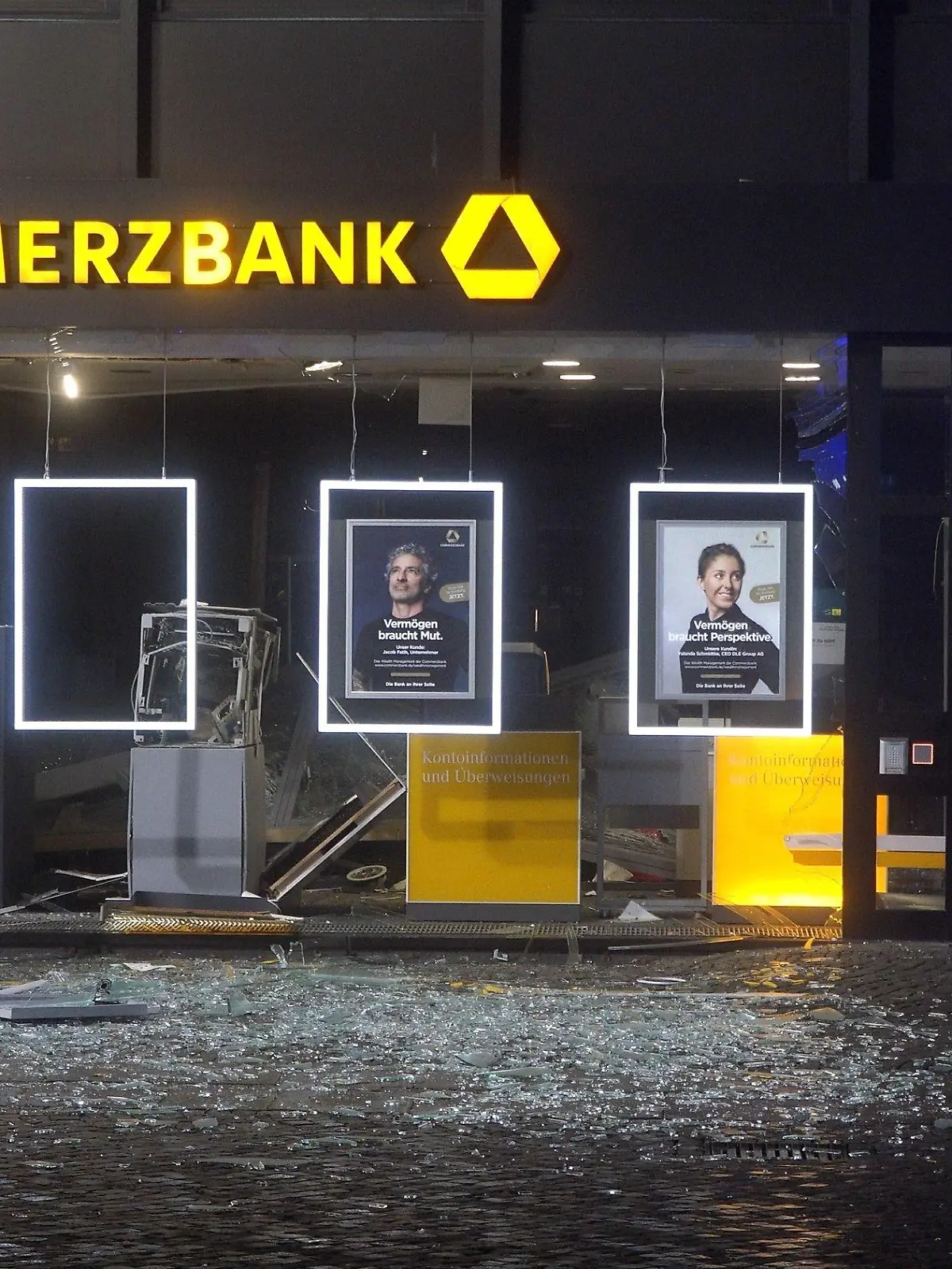 15.02.2023, Niedersachsen, Achim: Polizisten sind am Tatort im Einsatz. Unbekannte haben einen Geldautomaten in der Innenstadt von Achim (Landkreis Verden) gesprengt. Die Tat geschah am frühen Mittwochmorgen, wie die Polizei mitteilte. Dabei wurde die Glasfassade im unteren Bereich des Wohn- und Geschäftshauses, in dem der Automat stand, komplett zerstört. Foto: --/Nord-West-Media TV/dpa +++ dpa-Bildfunk +++