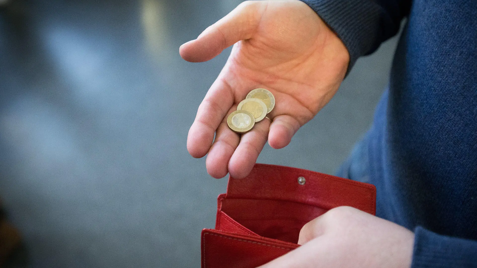 ARCHIV - 31.01.2017, Nordrhein-Westfalen, Paderborn: ILLUSTRATION - Münzen im Wert von fünf Euro liegen in einer Hand über einem Portemonnaie. Ab dieser Woche können rund 150 Millionen Euro für Menschen in sozialen Notlagen an die Kommunen in Nordrhein-Westfalen fließen. Das Geld solle helfen, Auswege aus Notlagen zu finden, sagte Ministerpräsident Hendrik Wüst (CDU) am Dienstag der Deutschen Presse-Agentur in Düsseldorf. (zu dpa: «150 Millionen jetzt abrufbereit zur Armutsbekämpfung in NRW») Foto: Friso Gentsch/dpa +++ dpa-Bildfunk +++