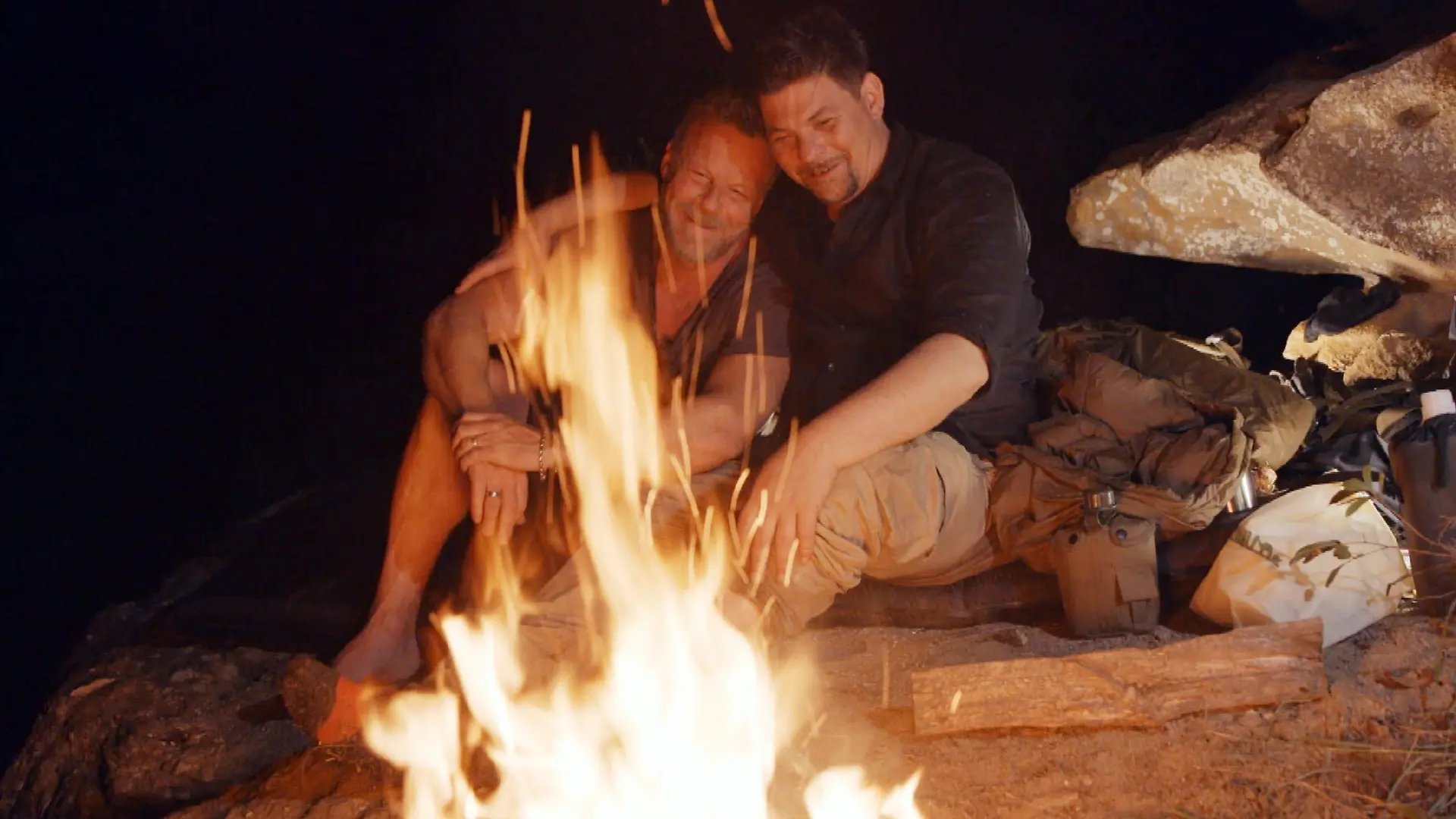 Jenke von Wilmsdorff und Tim Mälzer sitzen am Lagerfeuer