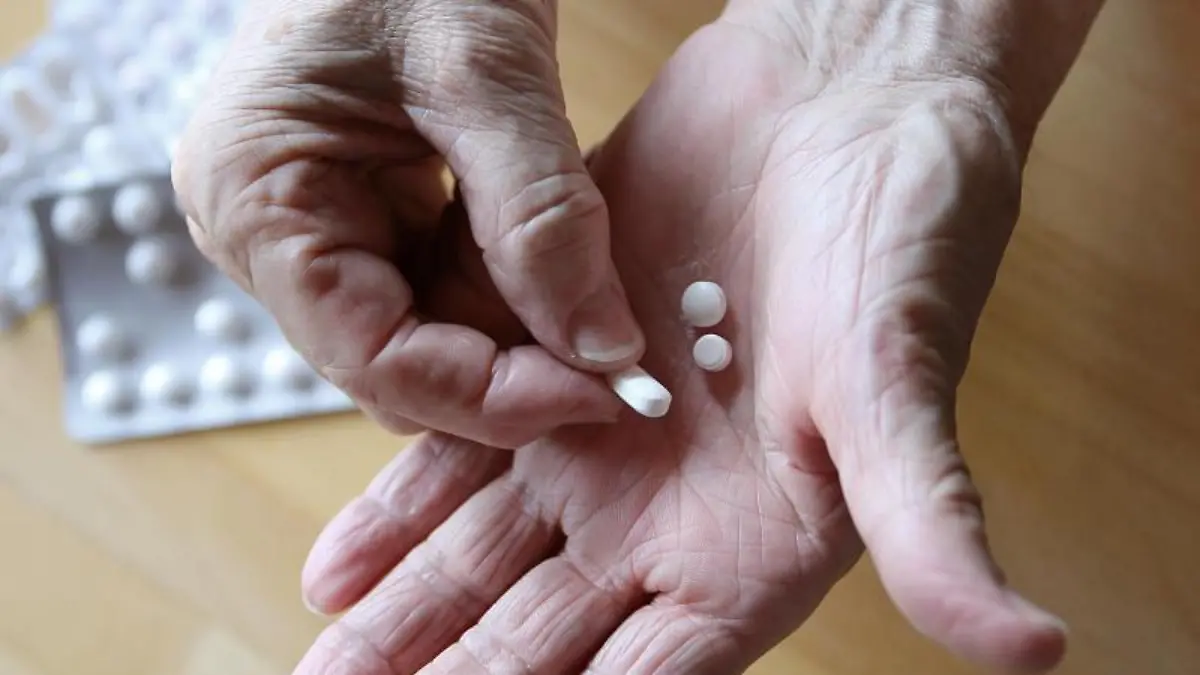 Eine ältere Frau hält Tabletten in der Hand