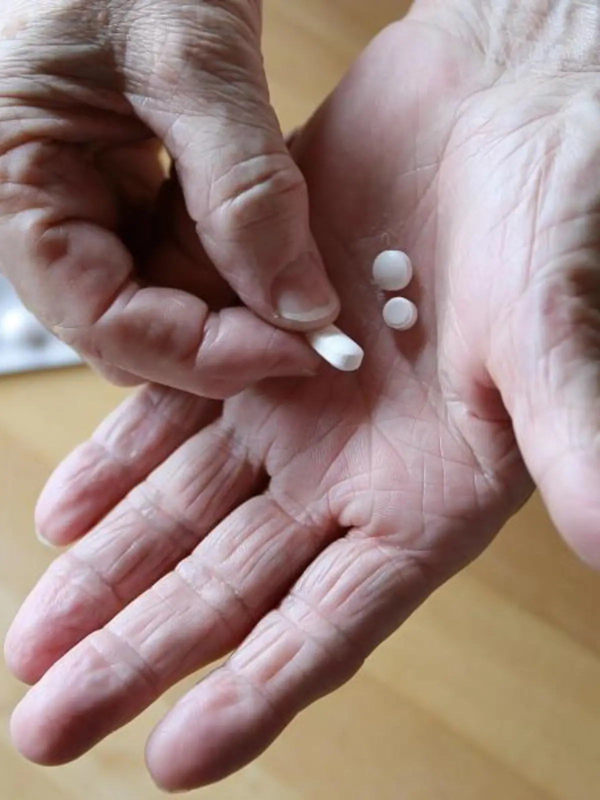 Eine ältere Frau hält Tabletten in der Hand