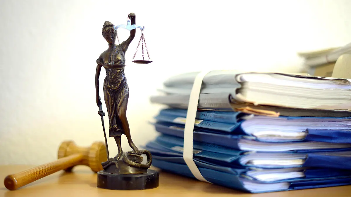 ARCHIV - ILLUSTRATION - Eine modellhafte Nachbildung der Justitia steht am 15.07.2014 im Raum eines Richters des Landgerichts Duisburg (Nordrhein-Westfalen) neben einem Holzhammer und einem Aktenstapel. Im Landgericht Bochum sollen Richter nun das Urteil gegen zwei Männer sprechen, die einen Autoverkäufer umgebracht haben sollen. Die Staatsanwaltschaft hatte für sie lebenslange Haft beantragt. (zu dpa vom 09.01.2018) Foto: Volker Hartmann/dpa +++(c) dpa - Bildfunk+++